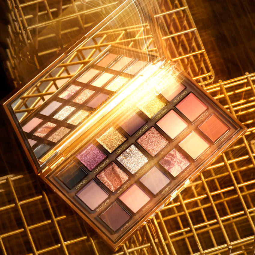 Makeup palette with various colors on a gold grid background