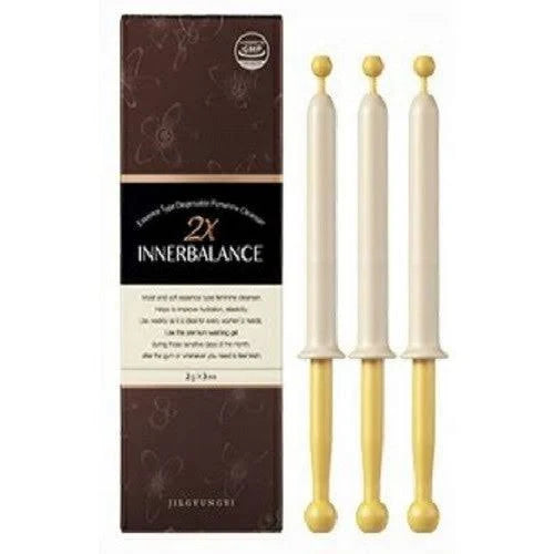 Three white candles with gold accents and a brown box labeled '2x Innerbalance' on a white background.
