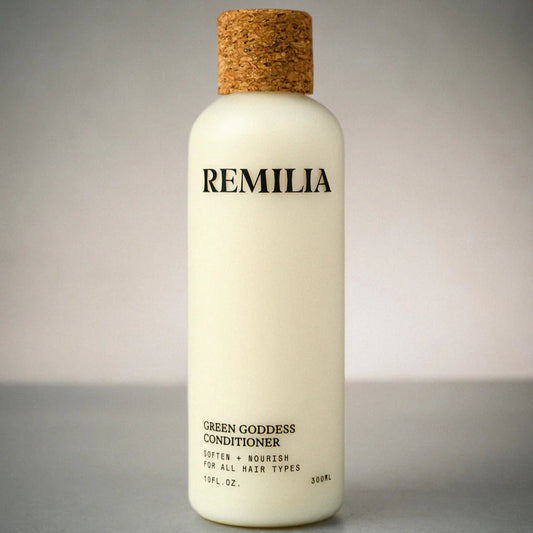 White bottle of Remilia Green Goddess Conditioner with a cork cap on a gray background