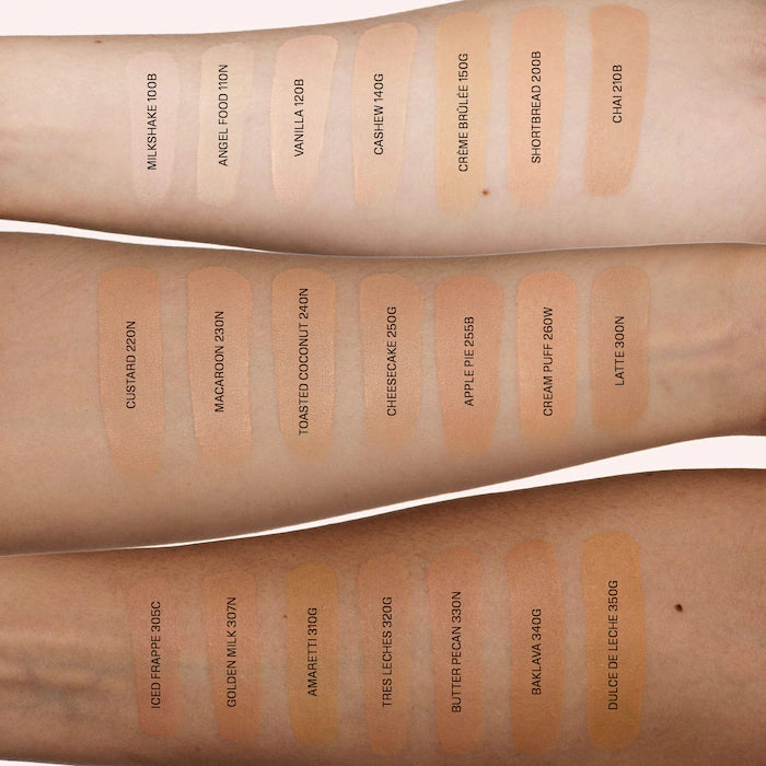 Makeup swatches on a person's arm with various shades labeled.